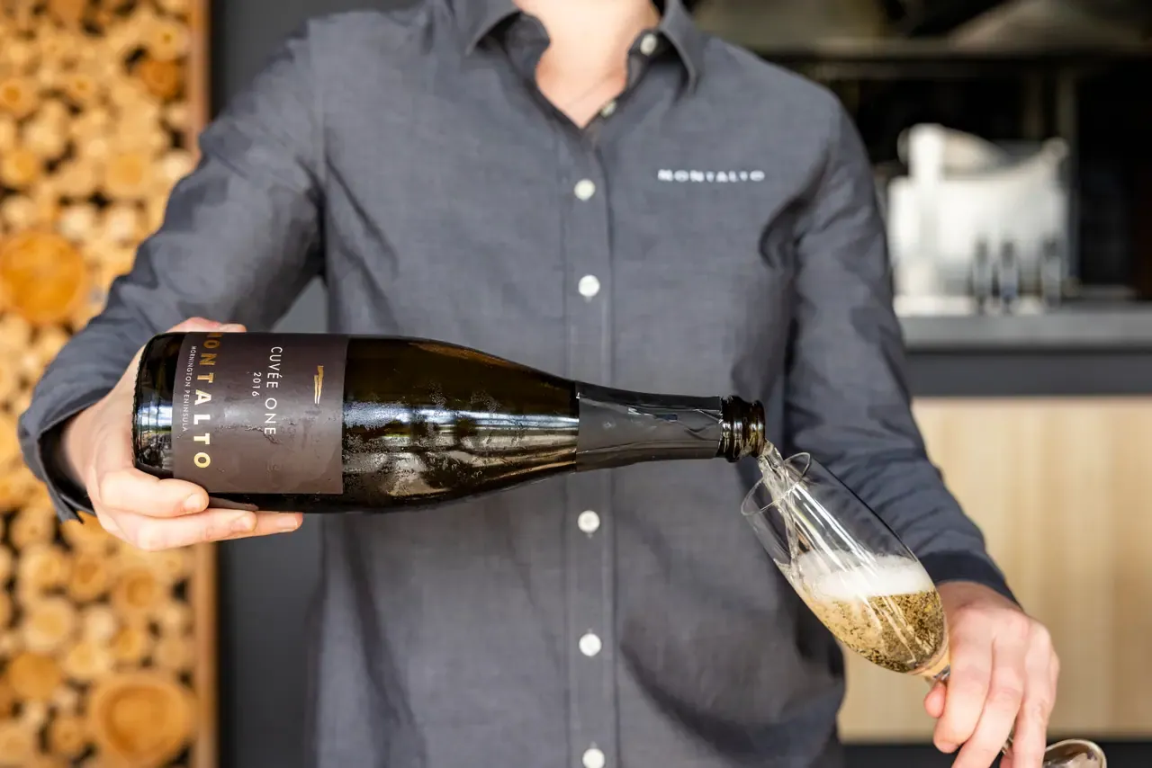 Staff member in a Montalto shirt pouring Montalto Cuvée One sparkling wine into a flute