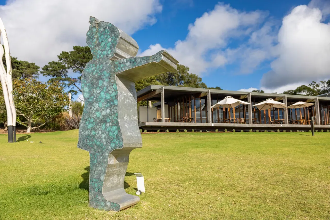 A patinated metal sculpture of a figure stands on the lawn in front of the Montalto restaurant and its white umbrellas