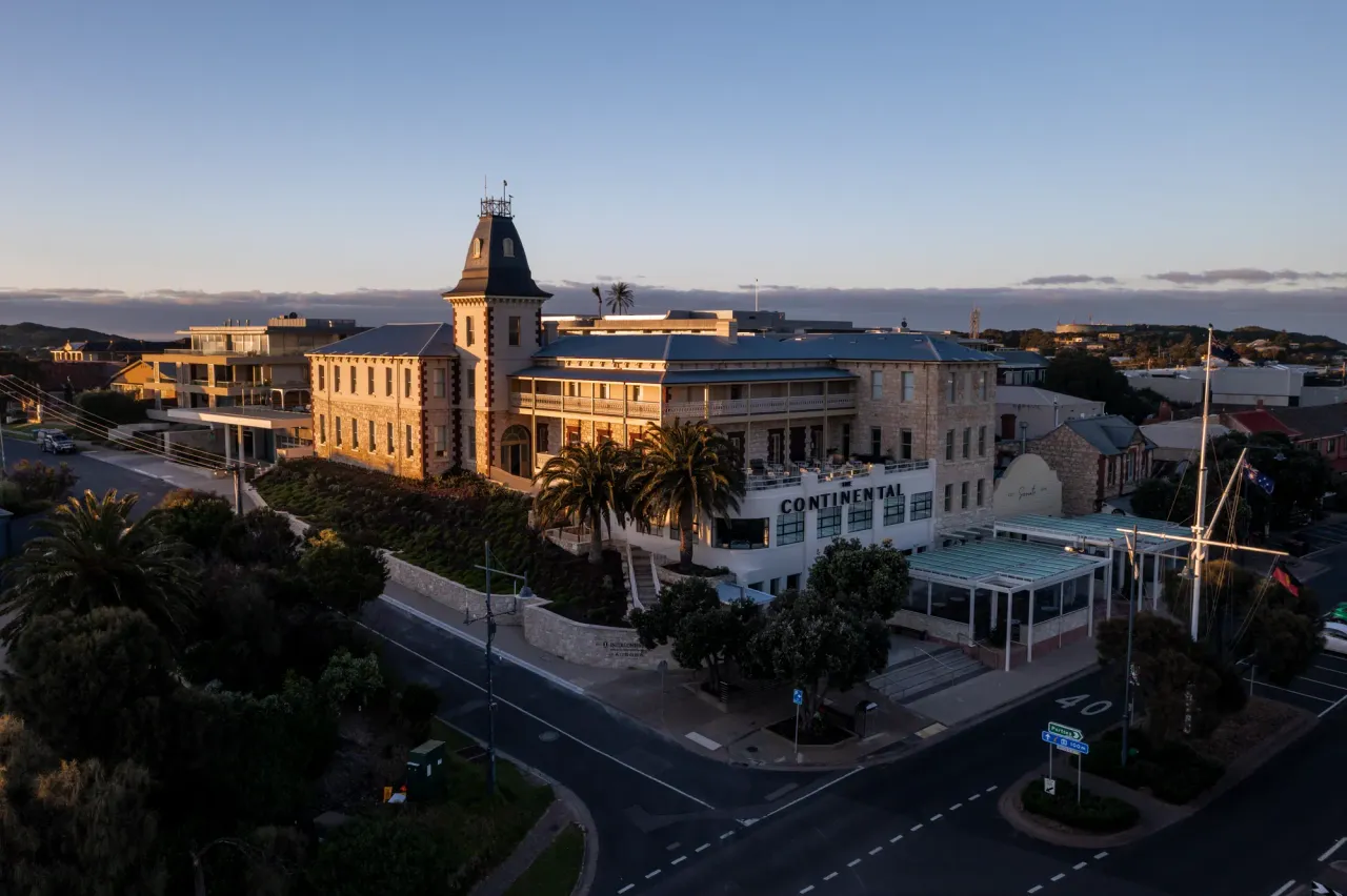 Aerial view of The Continental Sorrento, a limestone hotel with a slate-roofed tower, above a quiet street junction at first light