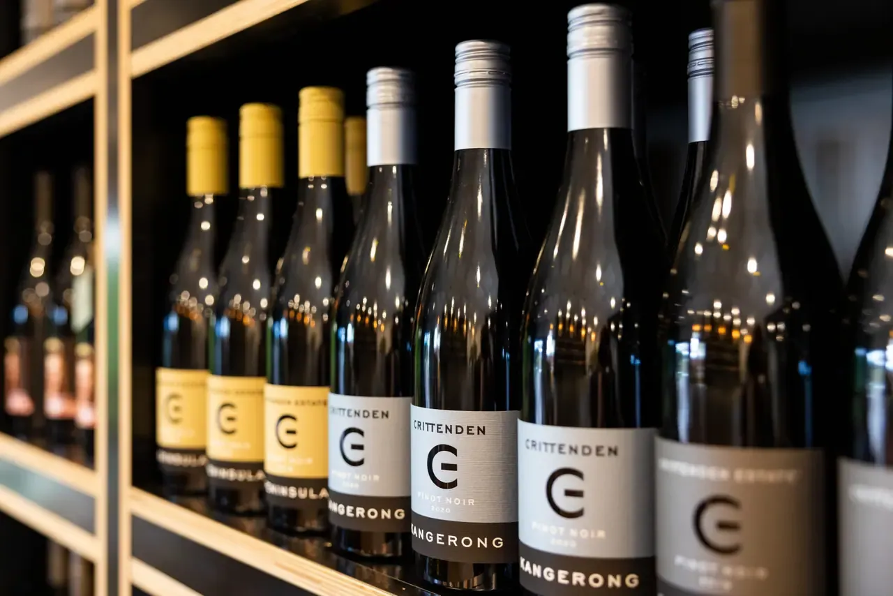 Crittenden Estate wines lined up on a timber shelf, including bottles of Kangerong Pinot Noir with the estate's C logo