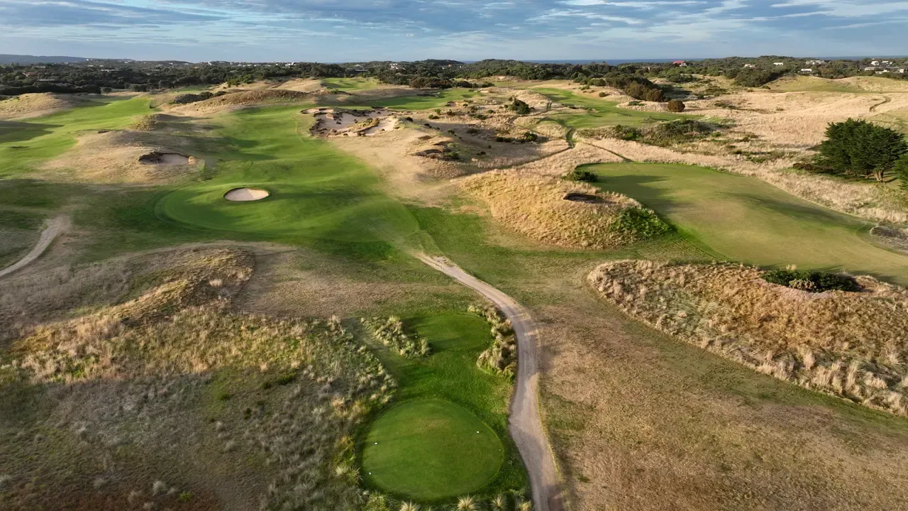 Aerial view of The Dunes Golf Links at Rye, with fairways and greens winding between sandy dunes and tall dry grass.