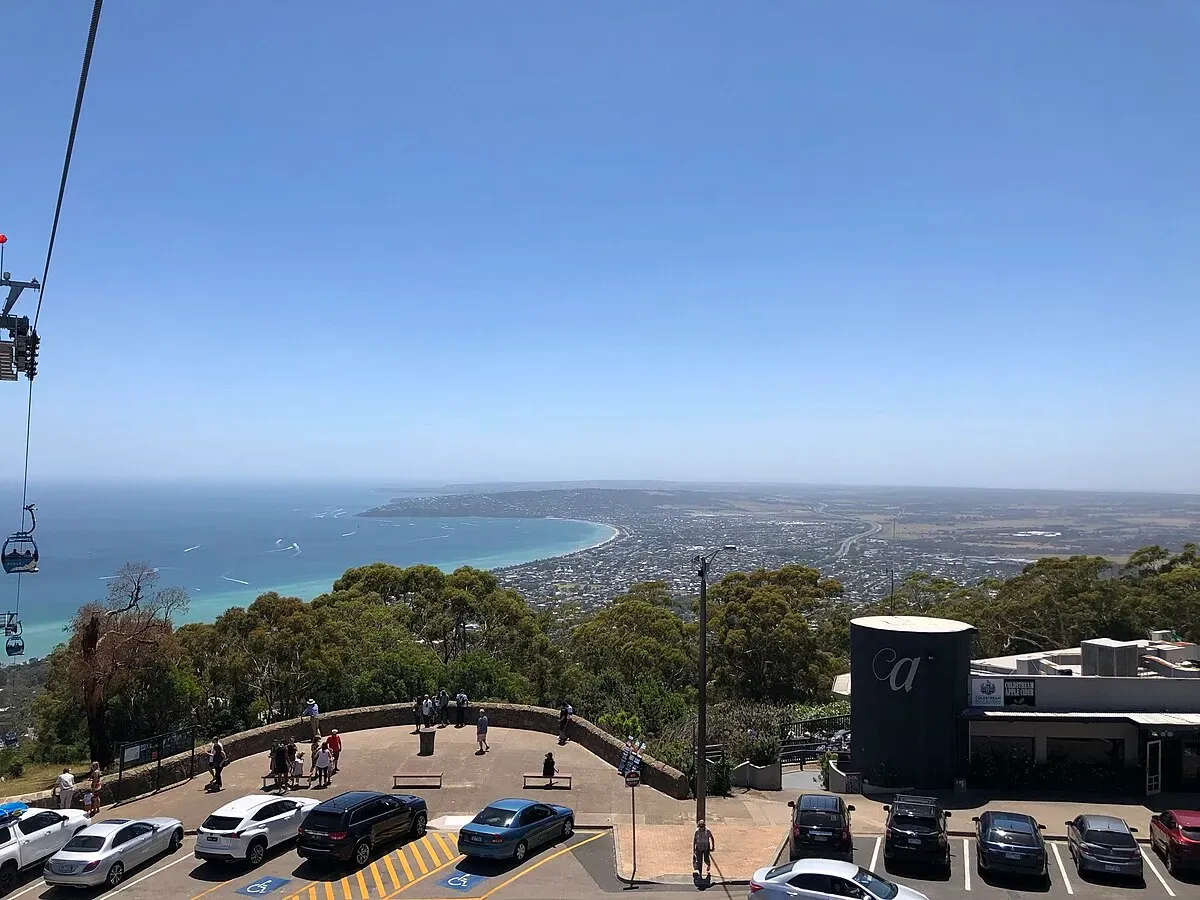 The view from the Arthurs Seat lookout over Port Phillip Bay, chairlift cables at left and visitors on the terrace above the car park.