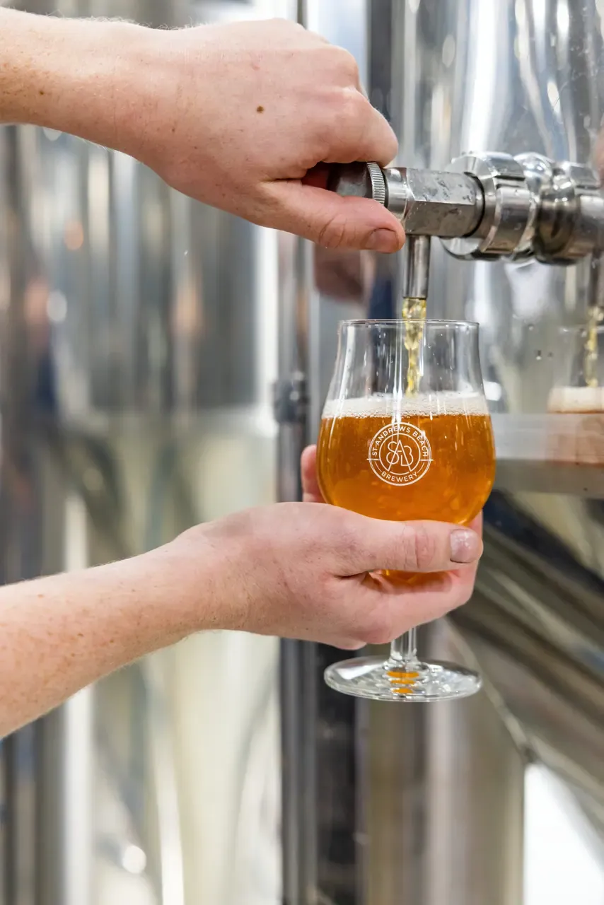 Amber beer poured straight from a steel brewing tank into a stemmed St Andrews Beach Brewery tasting glass