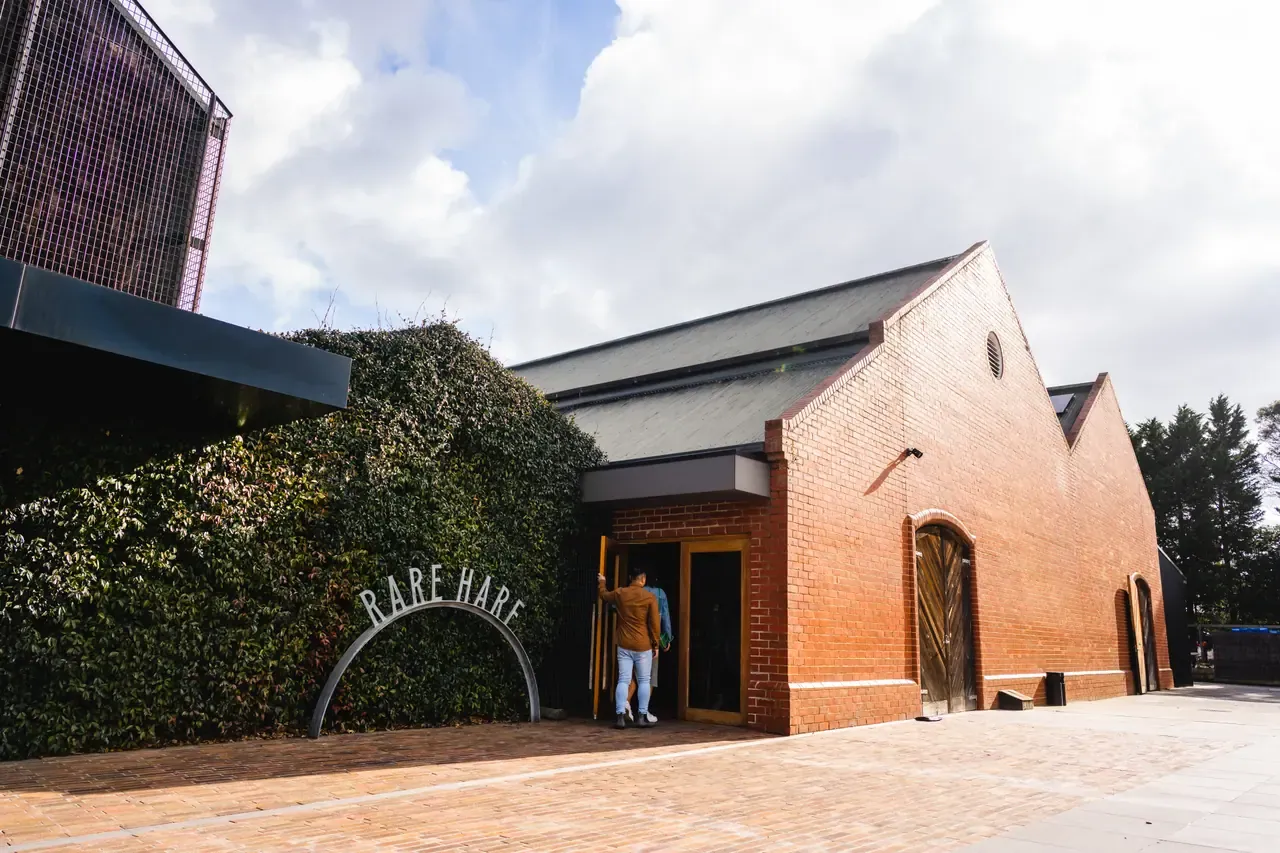 The red-brick Rare Hare building with its arched sign set against an ivy-covered wall and a paved forecourt