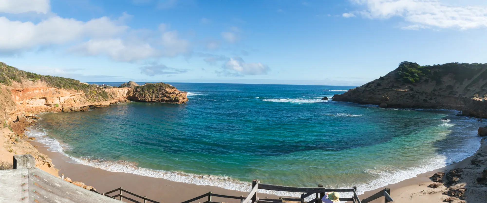 Turquoise water fills the sheltered cove at Diamond Bay near Sorrento Back Beach, ringed by sandstone cliffs and a timber stairway