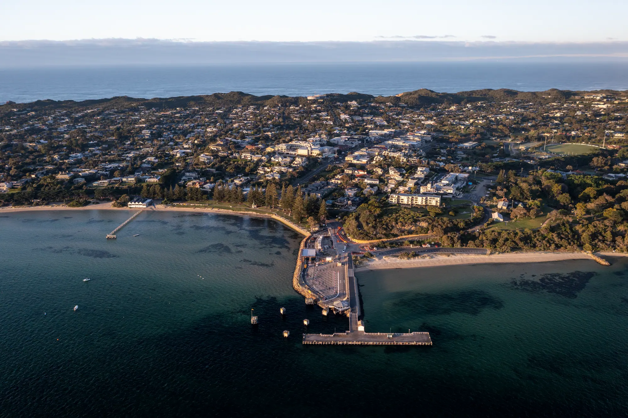 Aerial view of Sorrento at soft early light, with the ferry terminal pier reaching into the bay and the town and ocean beyond